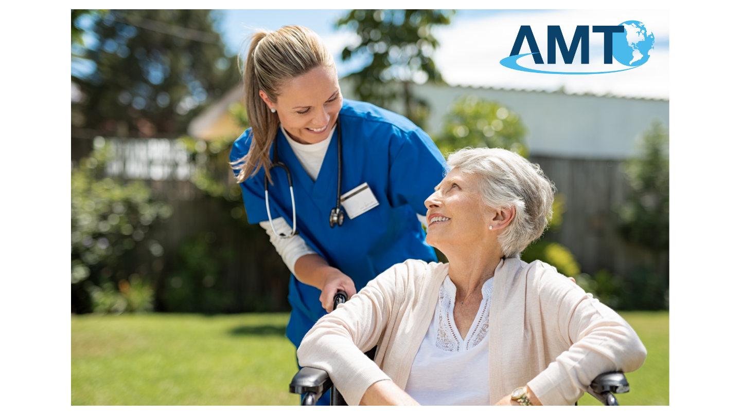 Smiling nurse in blue scrubs caring for an elderly woman in a wheelchair outdoors, with the AMT logo in the corner.