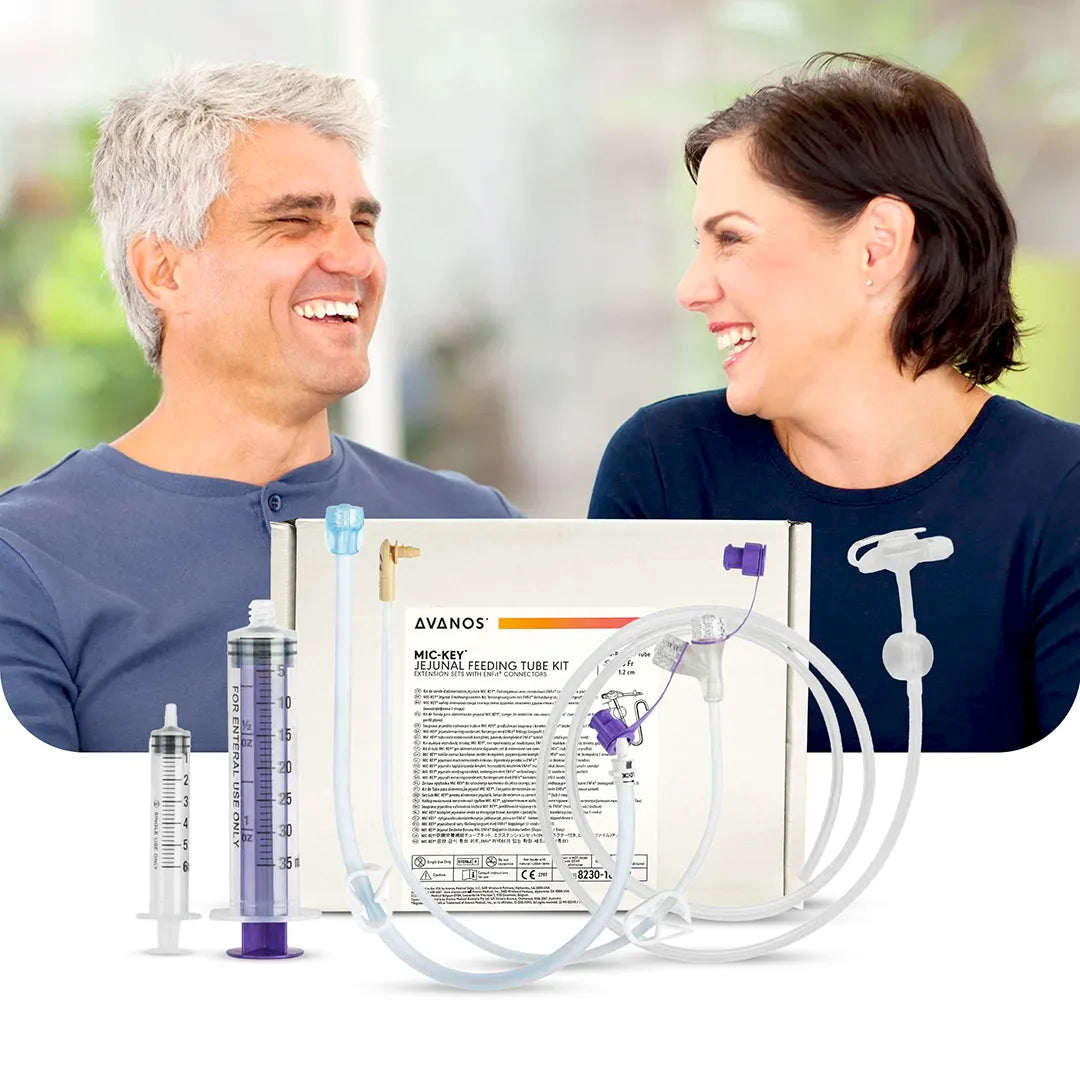 Smiling couple with Avanos MIC-KEY Jejunal Feeding Tube Kit in foreground, showing ENFit-compatible accessories, available at Medisa.