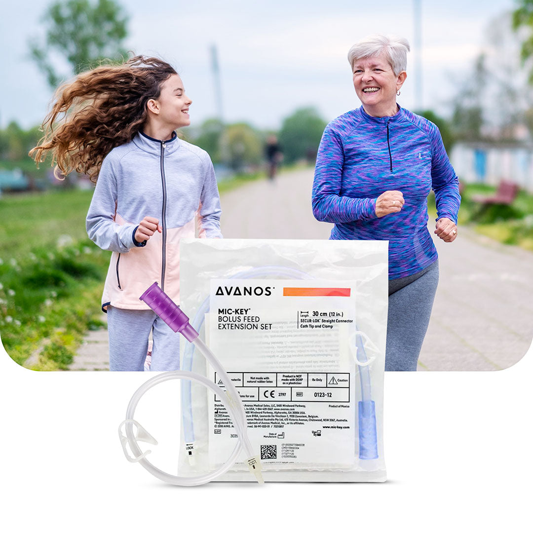 Active grandmother and granddaughter jogging outdoors, with Avanos MIC-KEY Bolus Feed Extension Set displayed in the foreground, symbolizing safe and convenient enteral feeding solutions for active lifestyles.