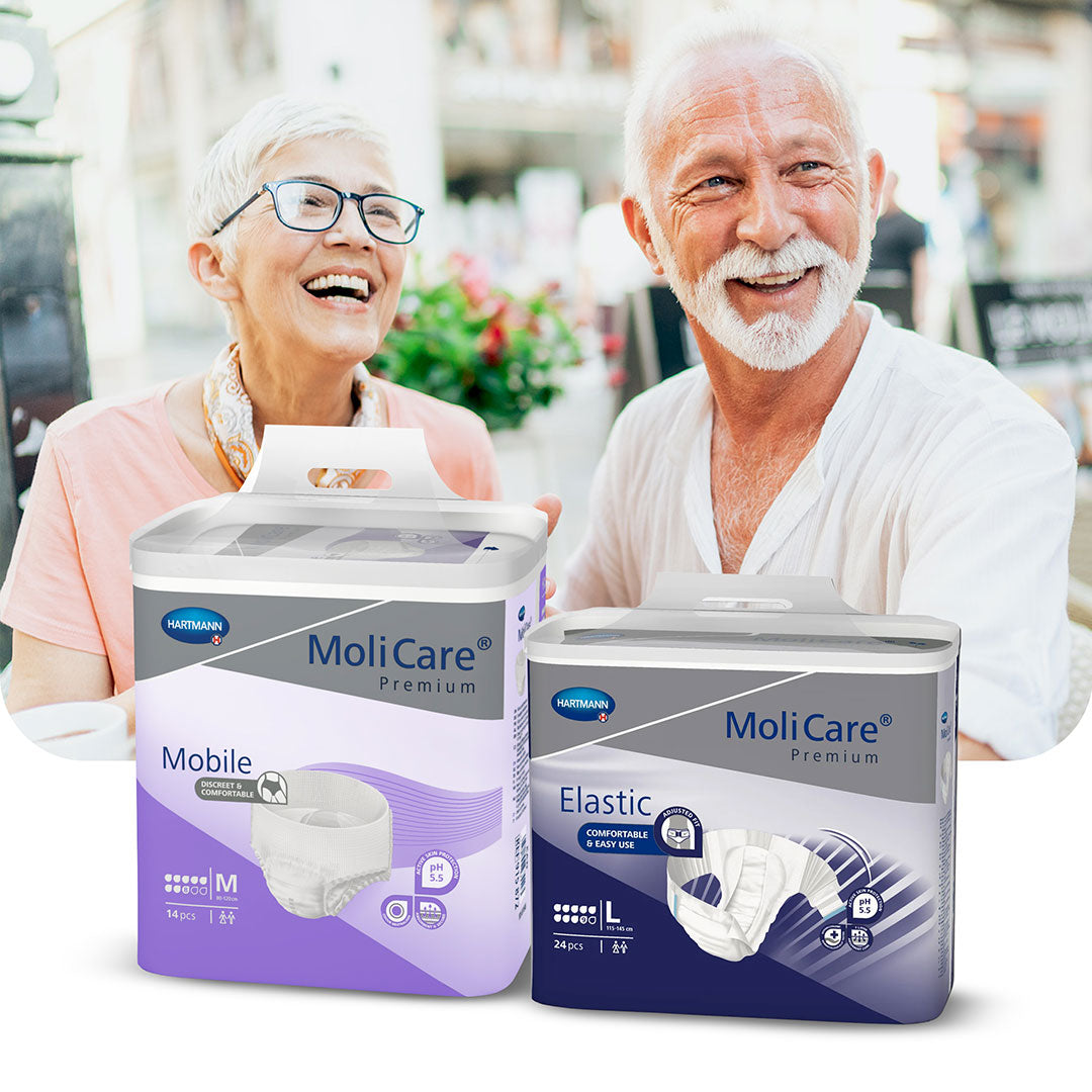 Smiling elderly couple enjoying time outdoors, with HARTMANN MoliCare Premium continence products (Mobile and Elastic) displayed in the foreground.